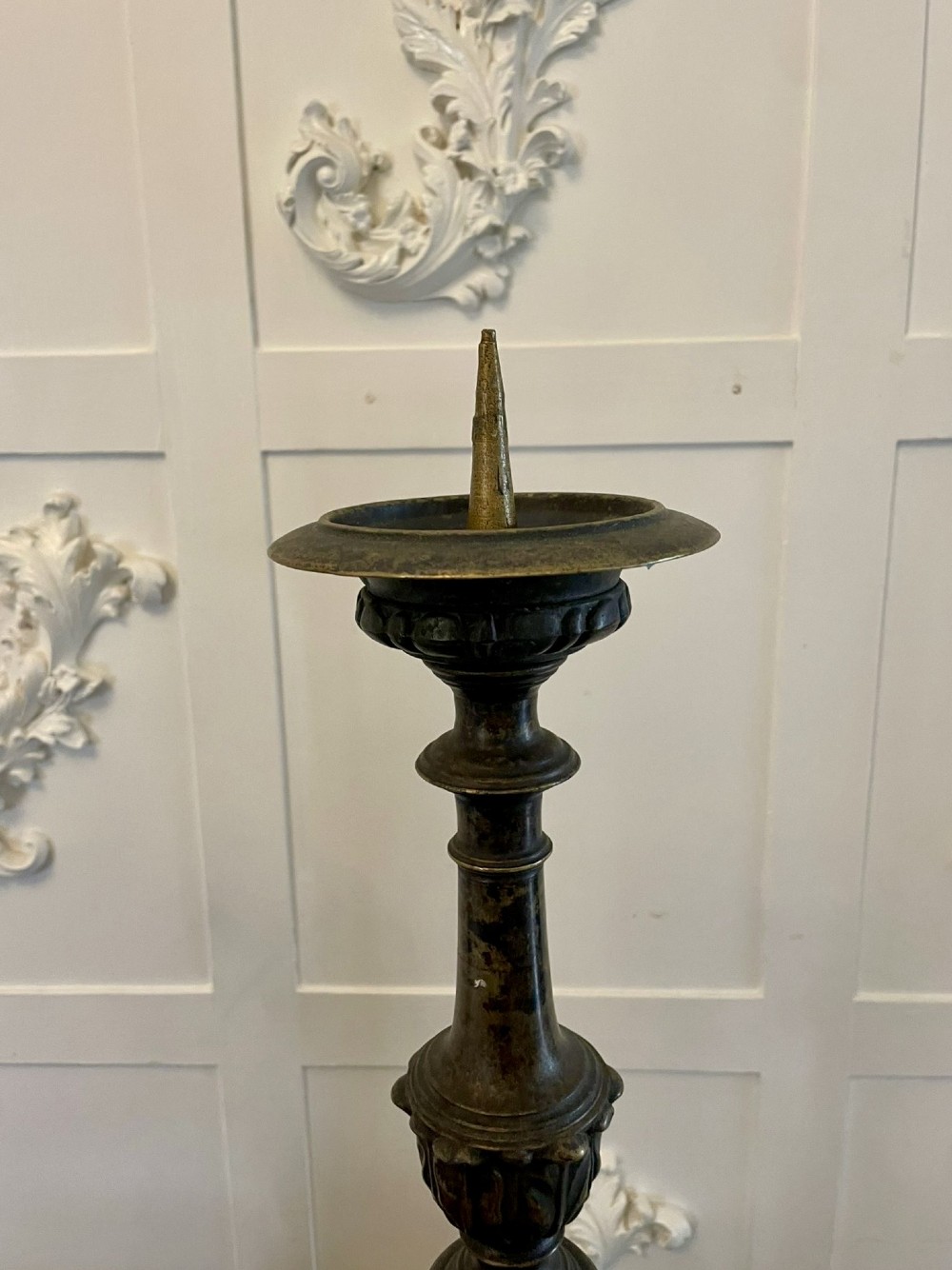 A pair of tall antique Victorian brass pricket candlesticks featuring ornate baluster shafts, foliate details, and spiked drip pans resting on decorative tripod bases. View III