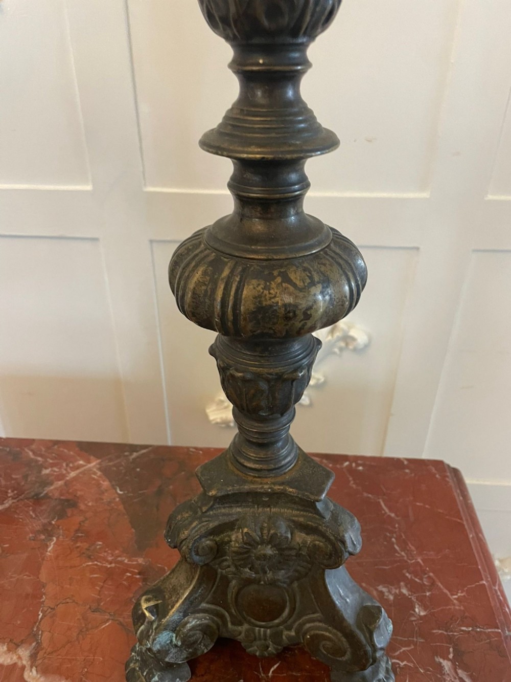 A pair of tall antique Victorian brass pricket candlesticks featuring ornate baluster shafts, foliate details, and spiked drip pans resting on decorative tripod bases. View IV