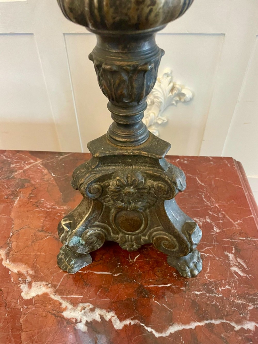 A pair of tall antique Victorian brass pricket candlesticks featuring ornate baluster shafts, foliate details, and spiked drip pans resting on decorative tripod bases. View V