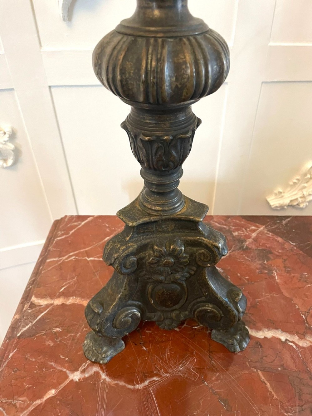 A pair of tall antique Victorian brass pricket candlesticks featuring ornate baluster shafts, foliate details, and spiked drip pans resting on decorative tripod bases. View VI