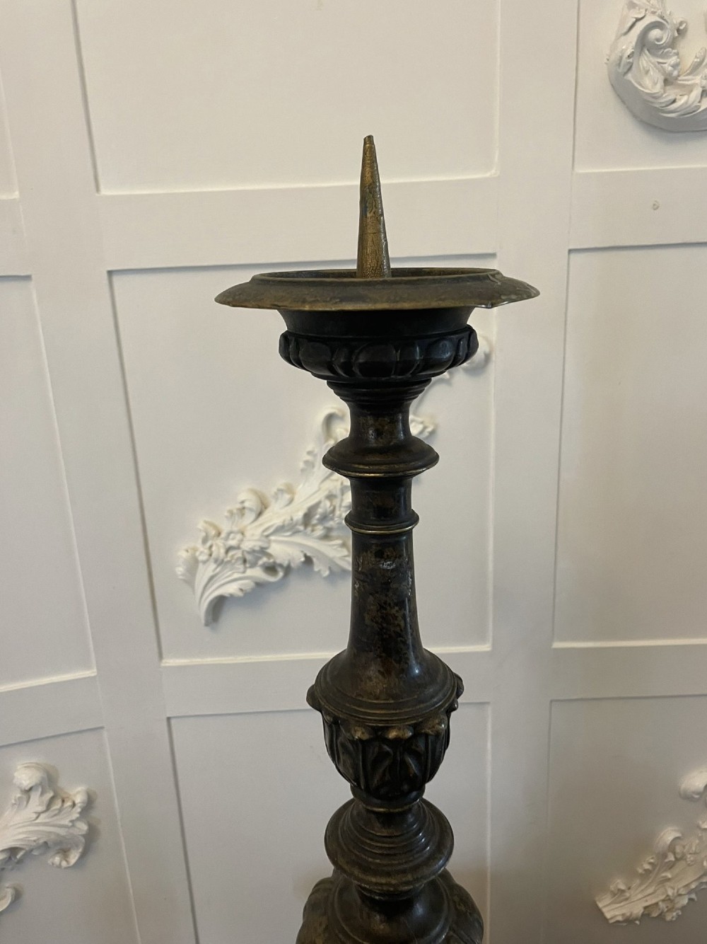 A pair of tall antique Victorian brass pricket candlesticks featuring ornate baluster shafts, foliate details, and spiked drip pans resting on decorative tripod bases. View VIII