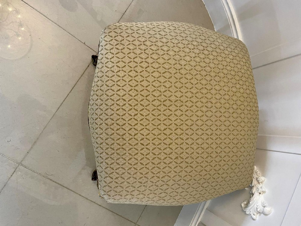 An antique Victorian low stool featuring carved walnut legs with gilt highlights and a beige geometric patterned upholstered top. View III