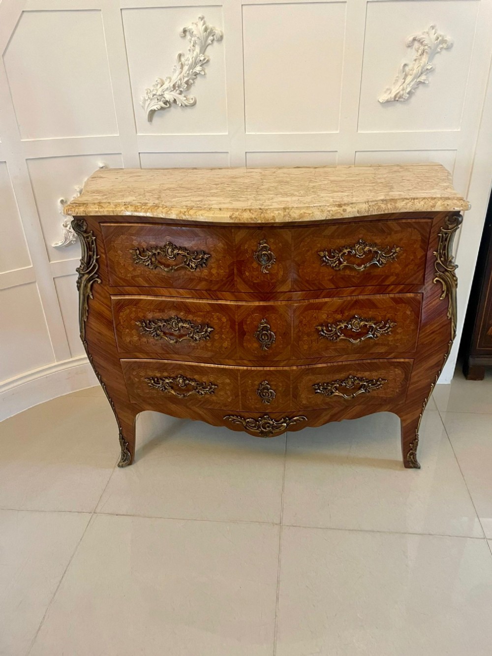 A French Louis XV style serpentine bombe commode featuring a variegated beige marble top, geometric parquetry timber veneer, three drawers, and decorative cast brass mounts. View XIII