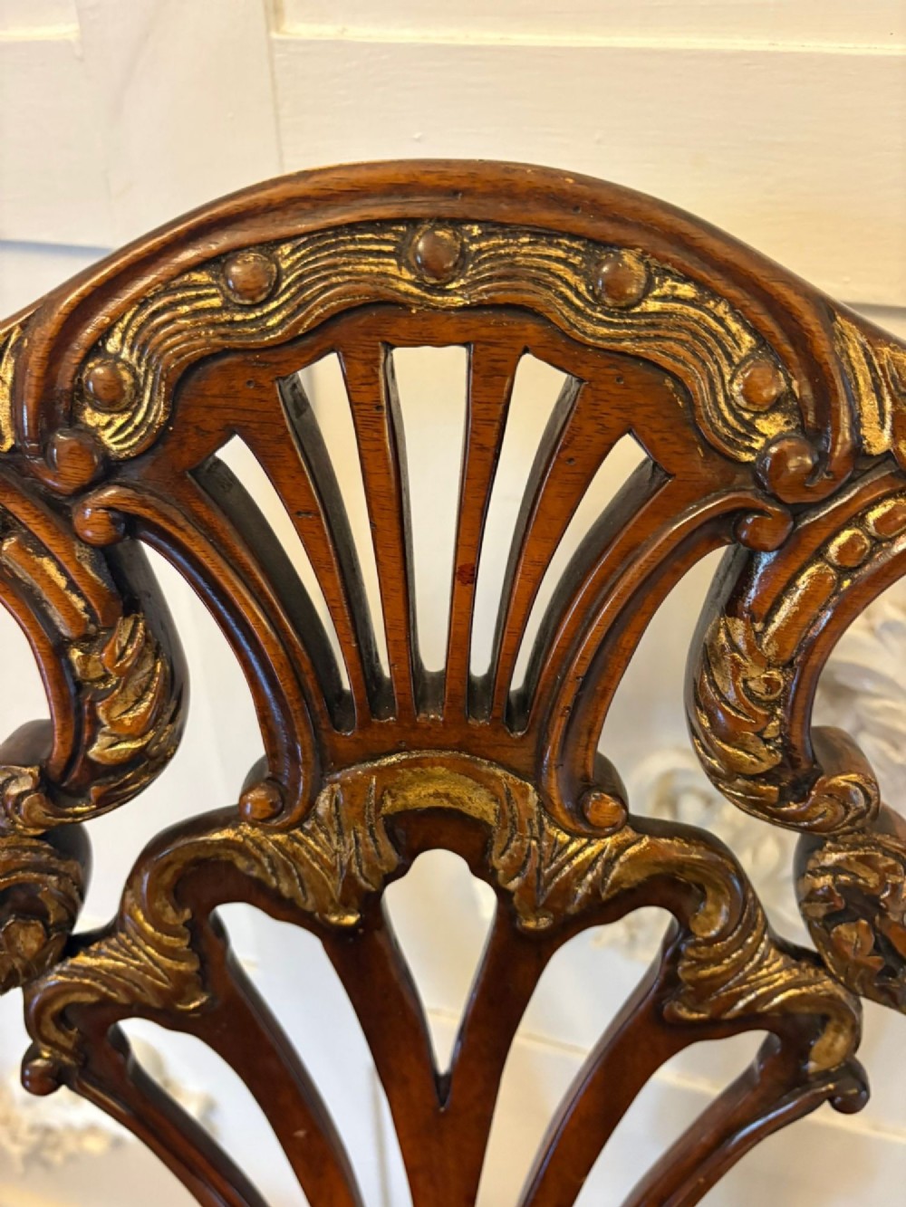 Set of eight Edwardian carved walnut dining chairs featuring pierced backrests, gilded highlights, cabriole legs, and dark brown button-tufted leather seats. View V