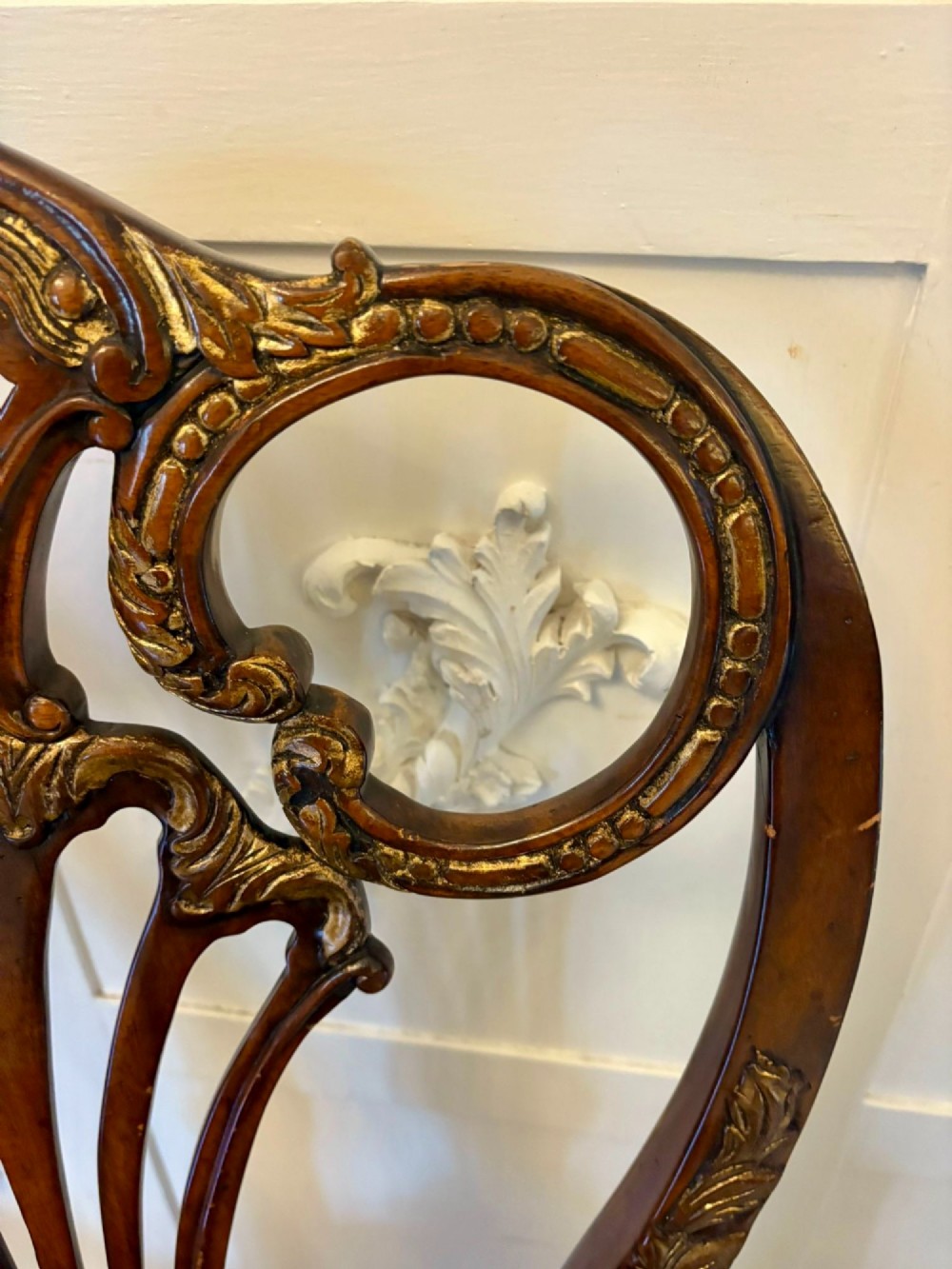 Set of eight Edwardian carved walnut dining chairs featuring pierced backrests, gilded highlights, cabriole legs, and dark brown button-tufted leather seats. View VI