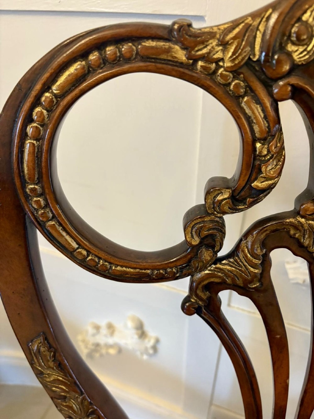 Set of eight Edwardian carved walnut dining chairs featuring pierced backrests, gilded highlights, cabriole legs, and dark brown button-tufted leather seats. View VII