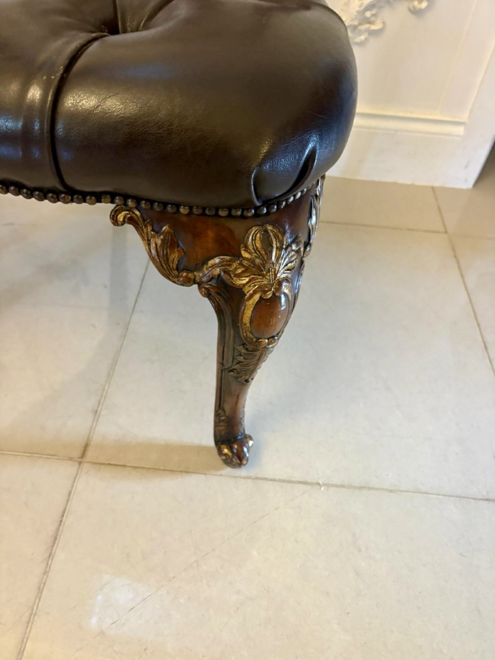 Set of eight Edwardian carved walnut dining chairs featuring pierced backrests, gilded highlights, cabriole legs, and dark brown button-tufted leather seats. View VIII
