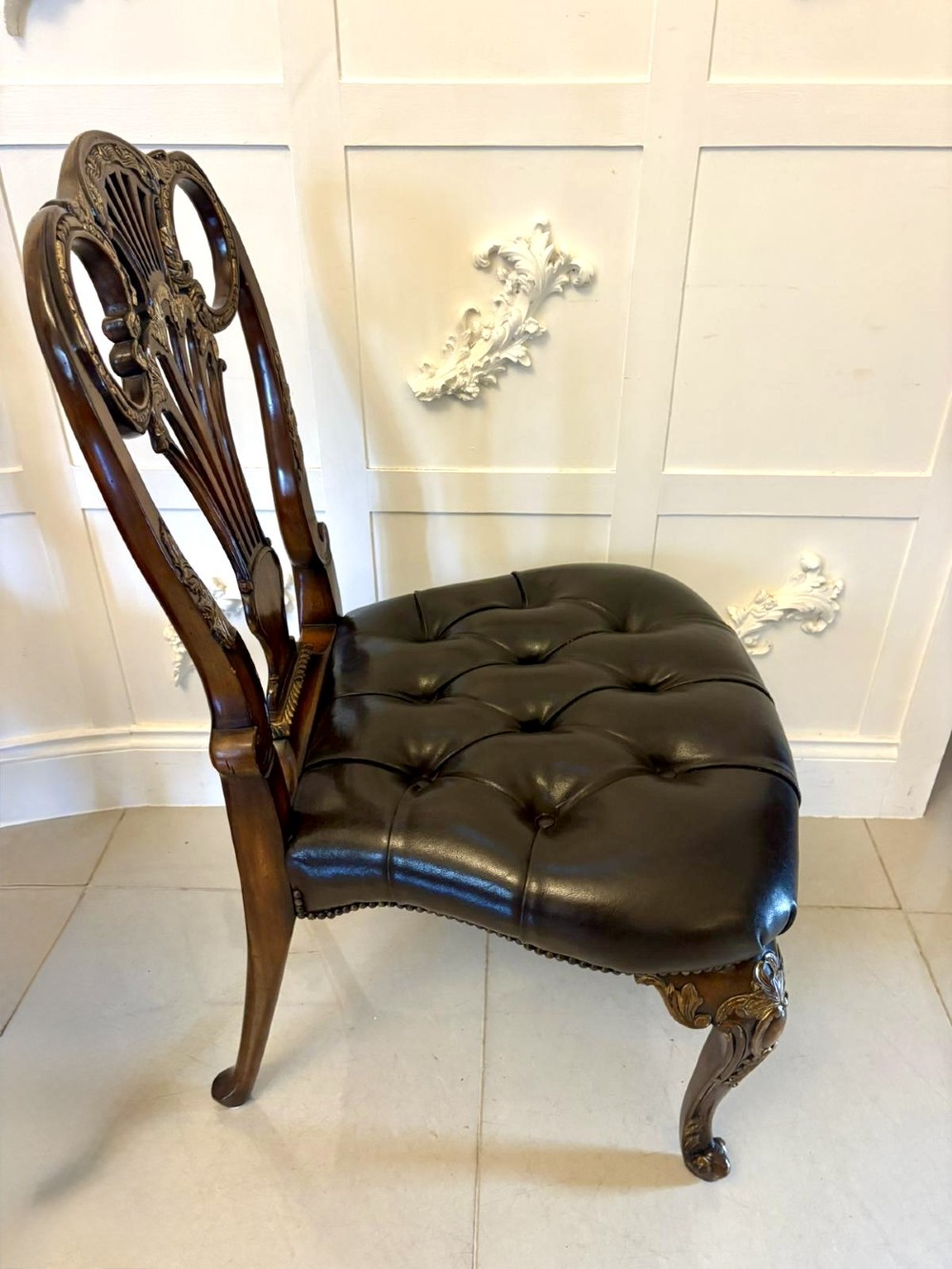 Set of eight Edwardian carved walnut dining chairs featuring pierced backrests, gilded highlights, cabriole legs, and dark brown button-tufted leather seats. View IX
