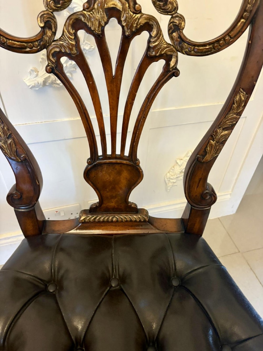 Set of eight Edwardian carved walnut dining chairs featuring pierced backrests, gilded highlights, cabriole legs, and dark brown button-tufted leather seats. View X