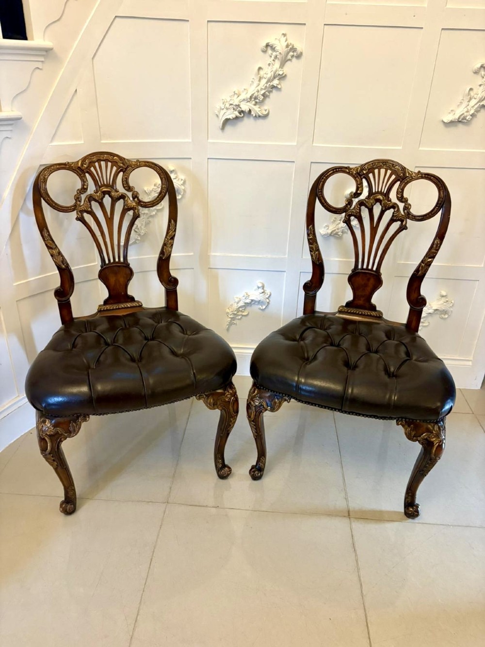 Set of eight Edwardian carved walnut dining chairs featuring pierced backrests, gilded highlights, cabriole legs, and dark brown button-tufted leather seats. View XIII