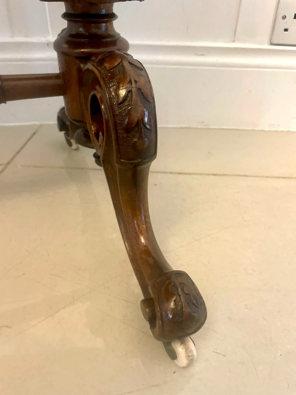 An antique Victorian oval lamp table crafted from burr walnut with turned end supports, a central stretcher, and carved legs with castors. View VIII