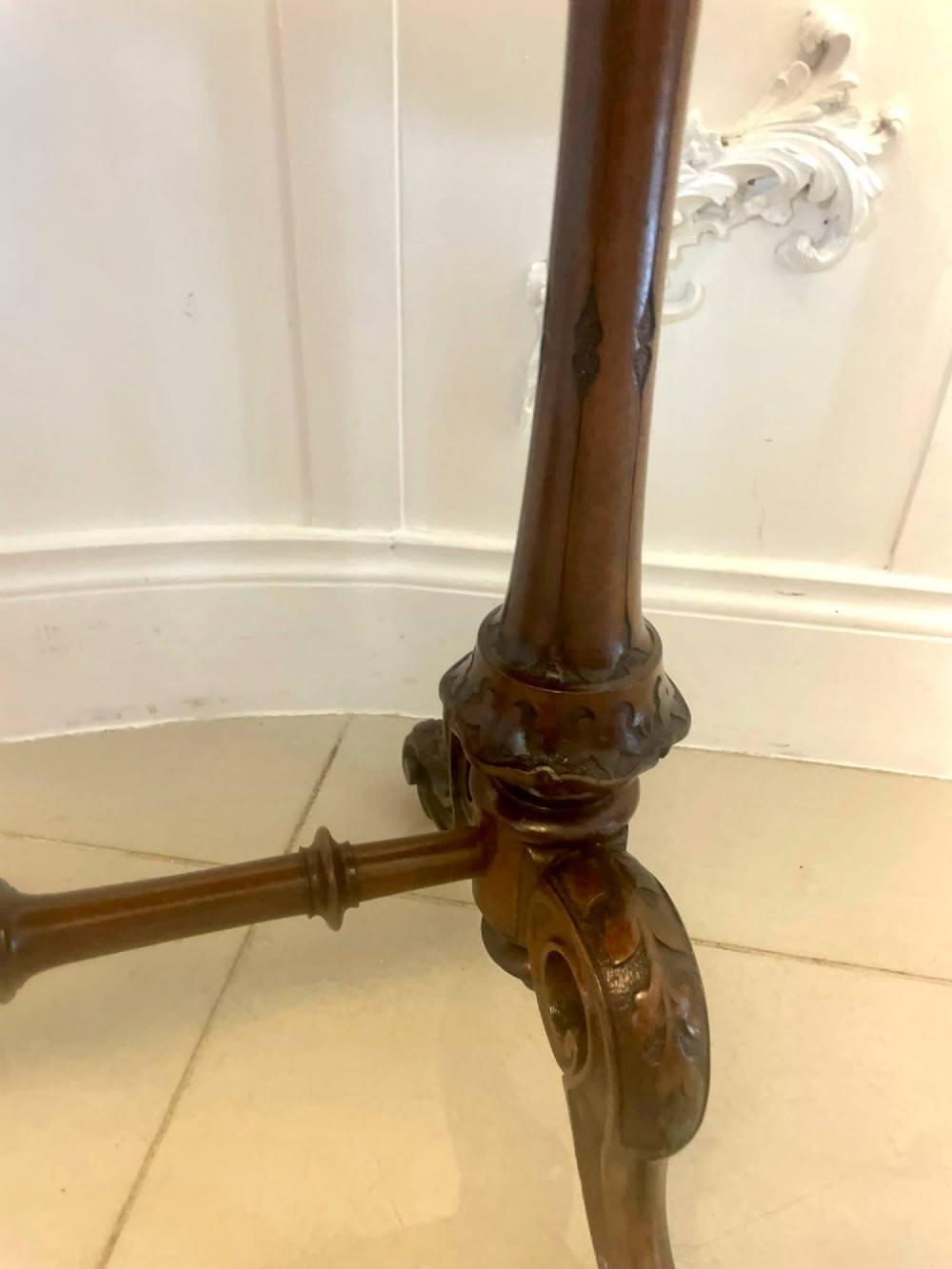 An antique Victorian oval lamp table crafted from burr walnut with turned end supports, a central stretcher, and carved legs with castors. View IX