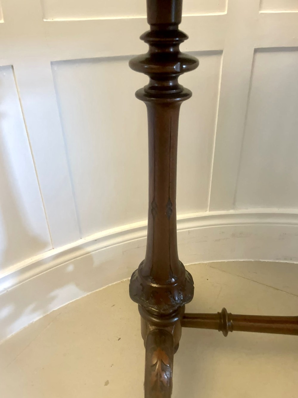 An antique Victorian oval lamp table crafted from burr walnut with turned end supports, a central stretcher, and carved legs with castors. View XI