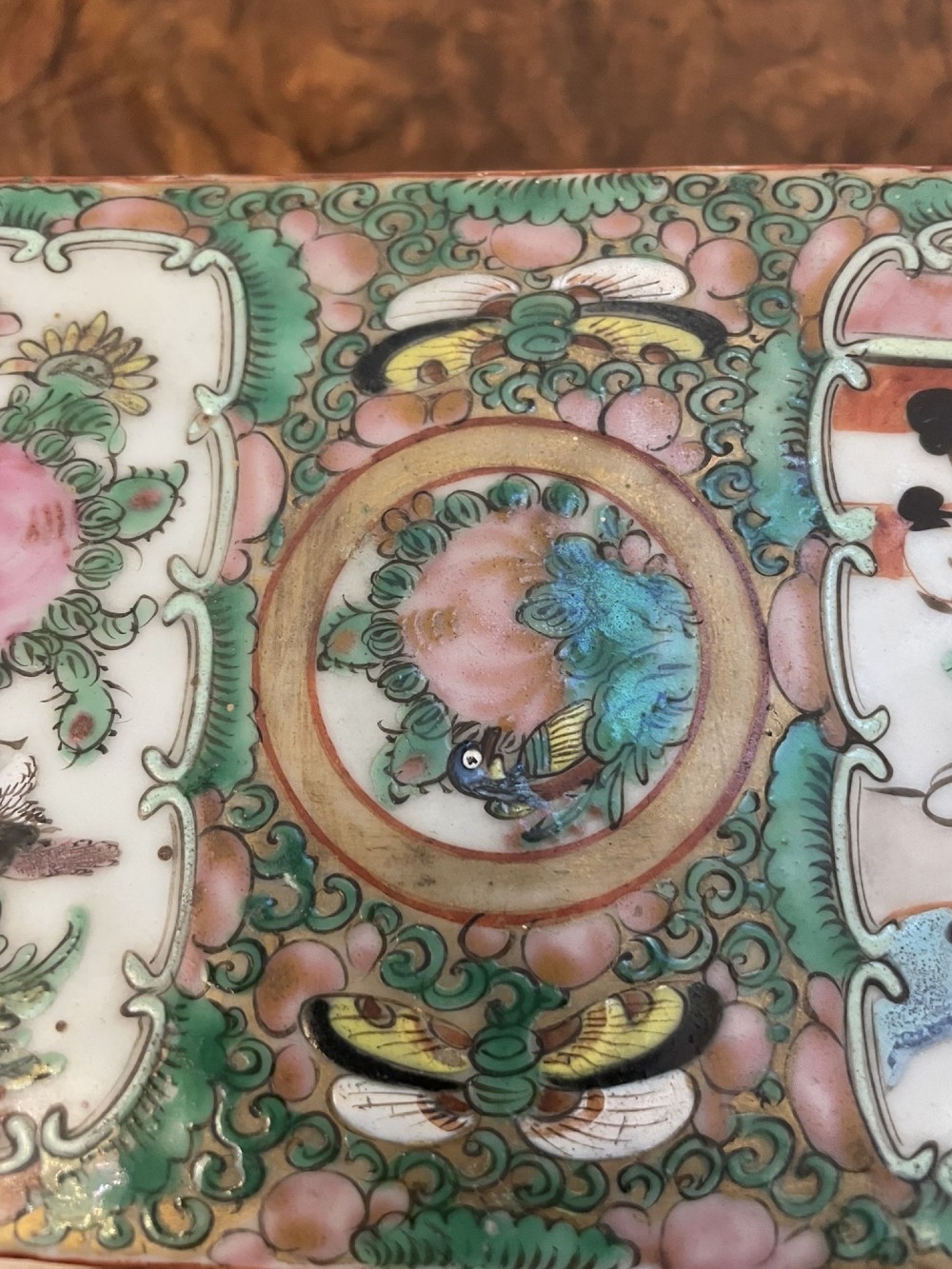 A rectangular 19th-century Chinese Canton Famille Rose porcelain box with lid decorated with hand-painted figure panels, pink flowers, and green scroll motifs. View V