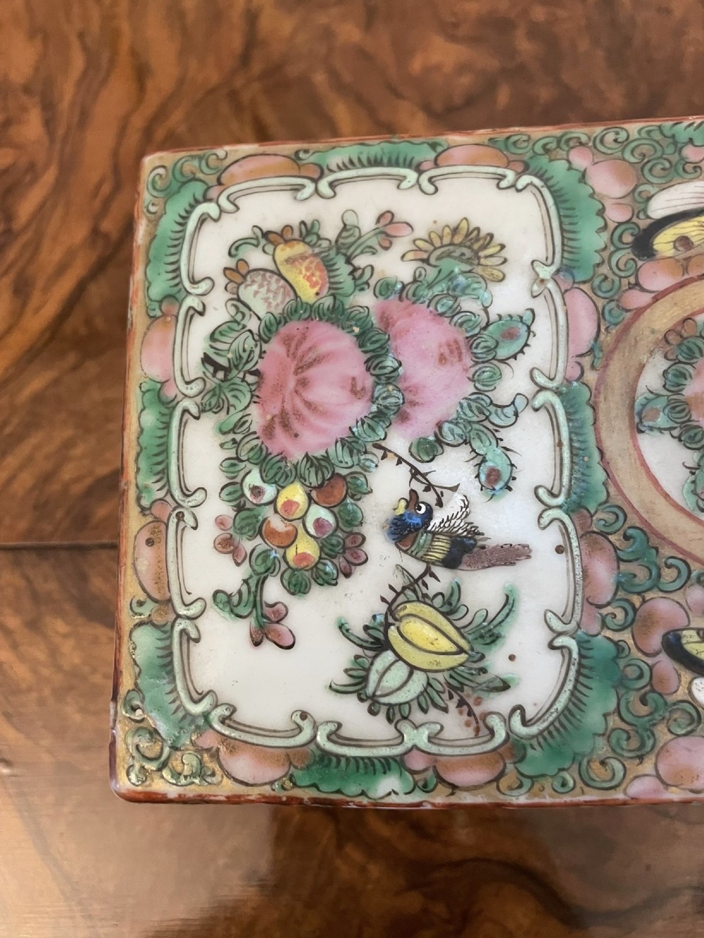 A rectangular 19th-century Chinese Canton Famille Rose porcelain box with lid decorated with hand-painted figure panels, pink flowers, and green scroll motifs. View VI