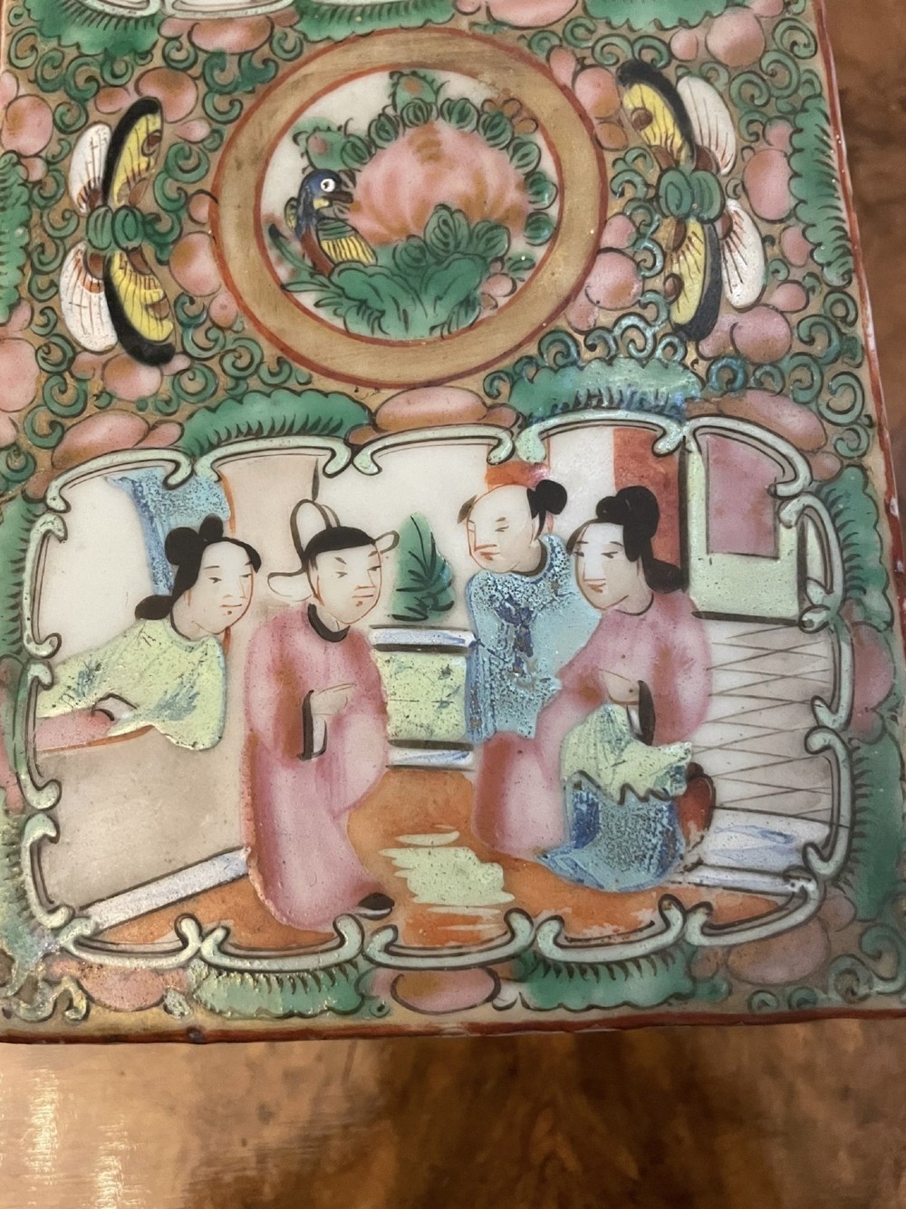 A rectangular 19th-century Chinese Canton Famille Rose porcelain box with lid decorated with hand-painted figure panels, pink flowers, and green scroll motifs. View VII