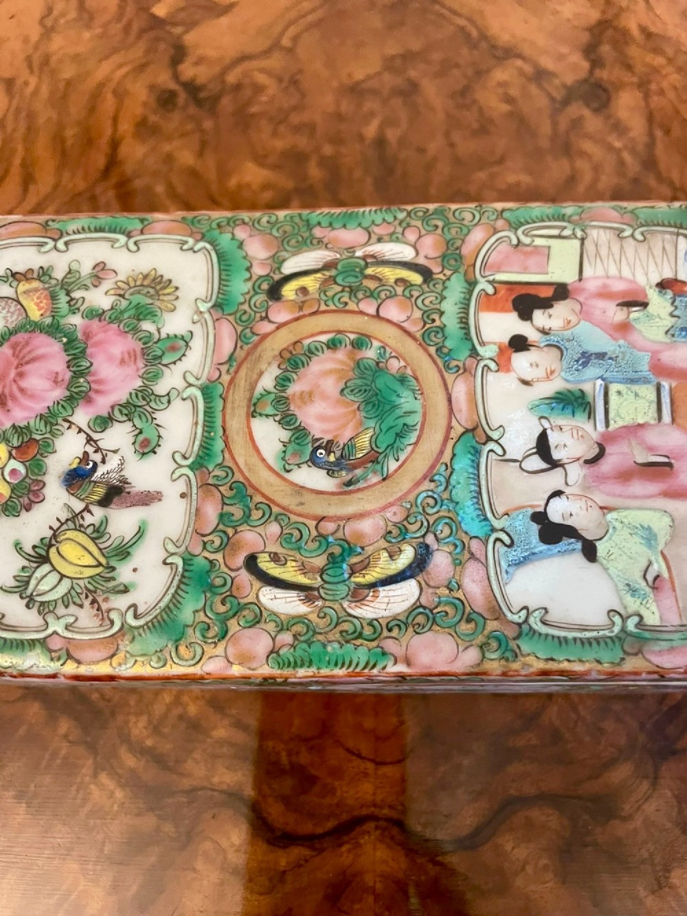 A rectangular 19th-century Chinese Canton Famille Rose porcelain box with lid decorated with hand-painted figure panels, pink flowers, and green scroll motifs. View X