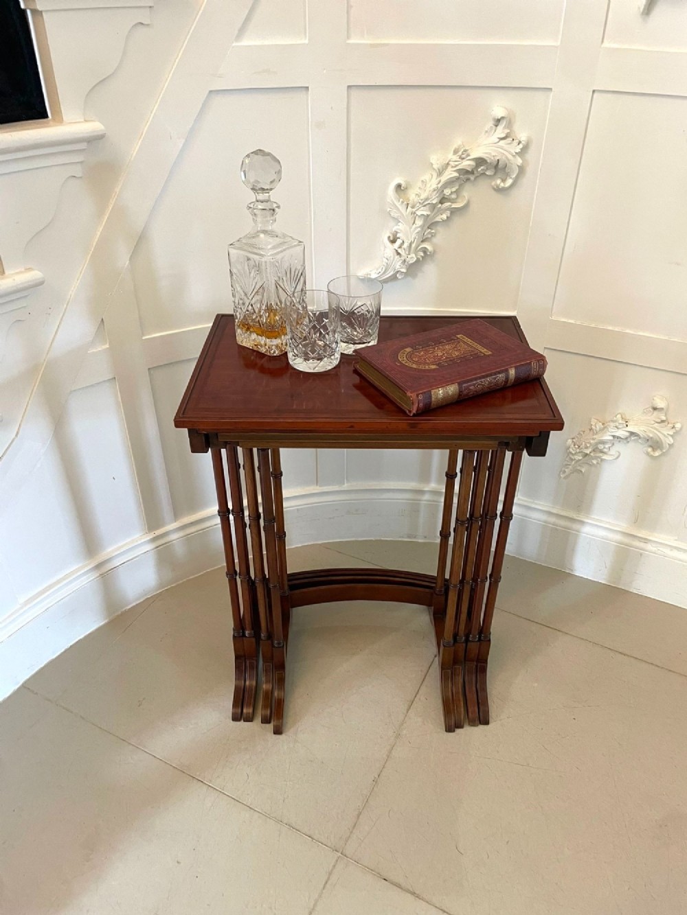 A set of four graduated Edwardian mahogany nesting tables with inlaid tops and slender turned legs arranged in a stepped display. View II
