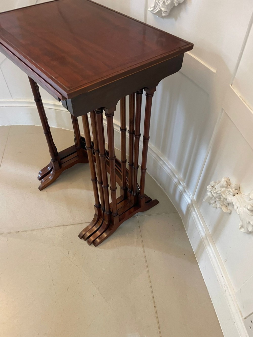 A set of four graduated Edwardian mahogany nesting tables with inlaid tops and slender turned legs arranged in a stepped display. View VIII