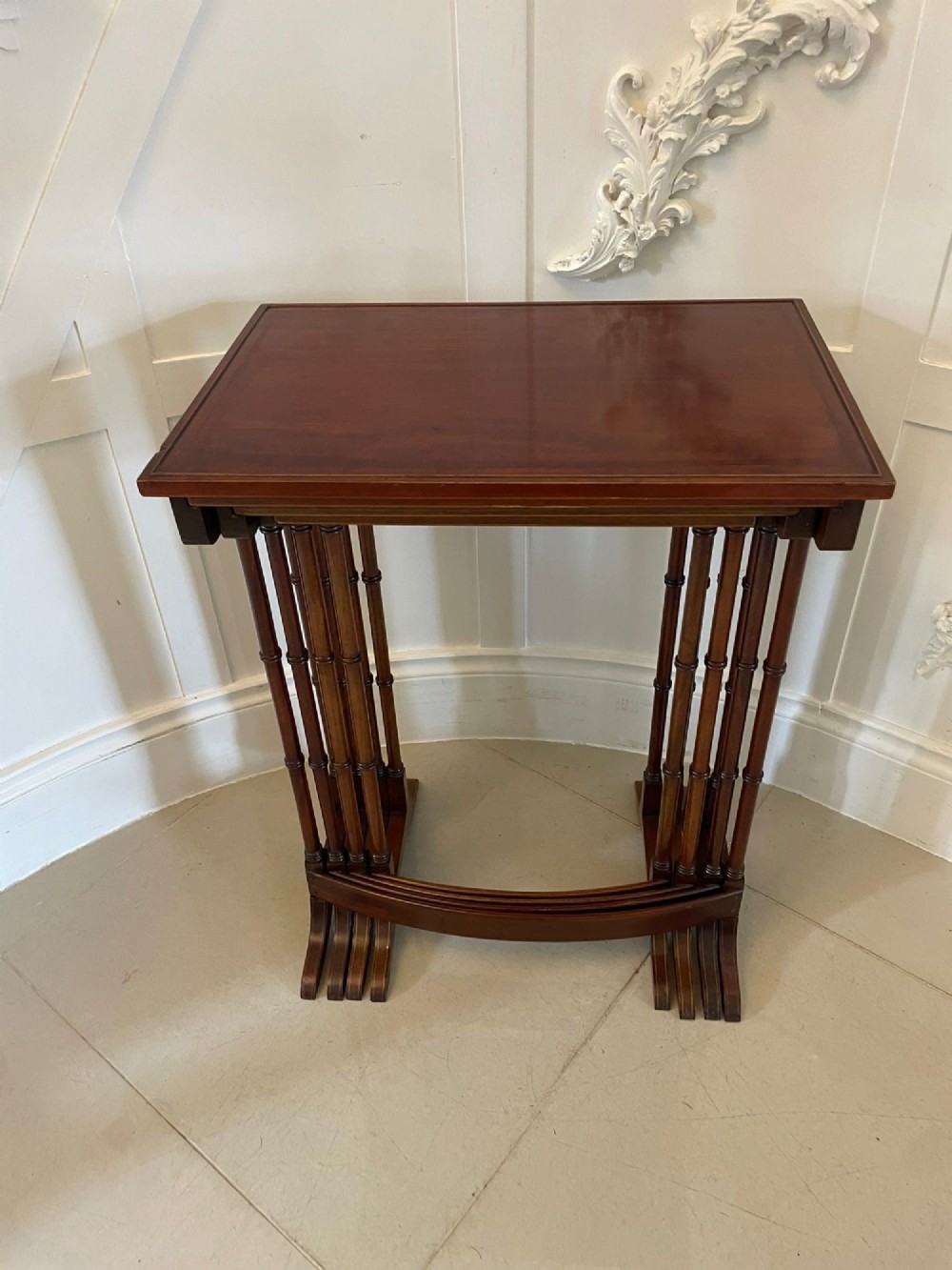 A set of four graduated Edwardian mahogany nesting tables with inlaid tops and slender turned legs arranged in a stepped display. View IX