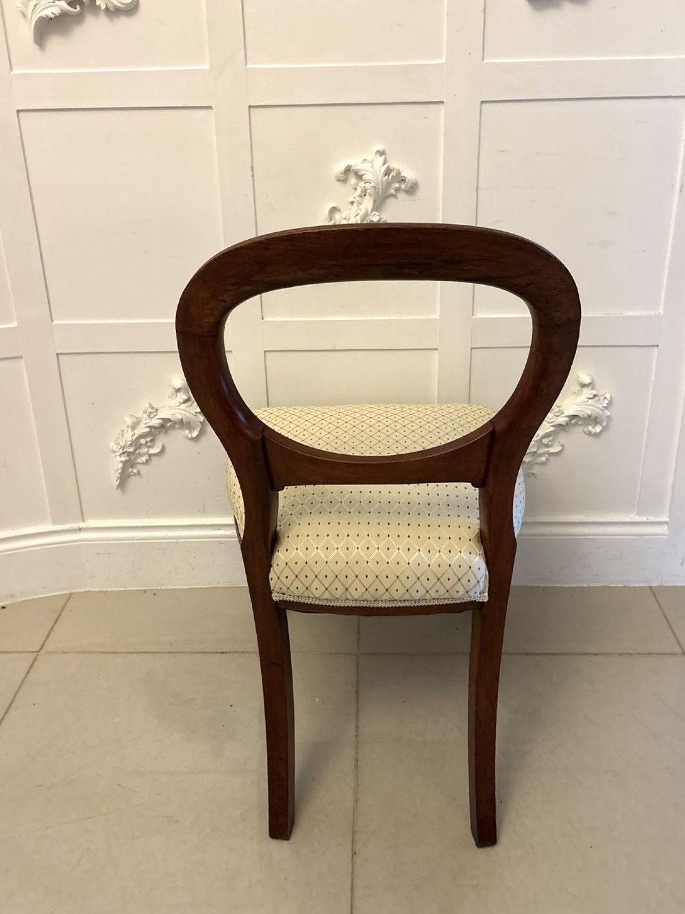 A set of four antique Victorian mahogany dining chairs featuring open balloon-shaped backrests, turned front legs, and cream patterned upholstery. View II