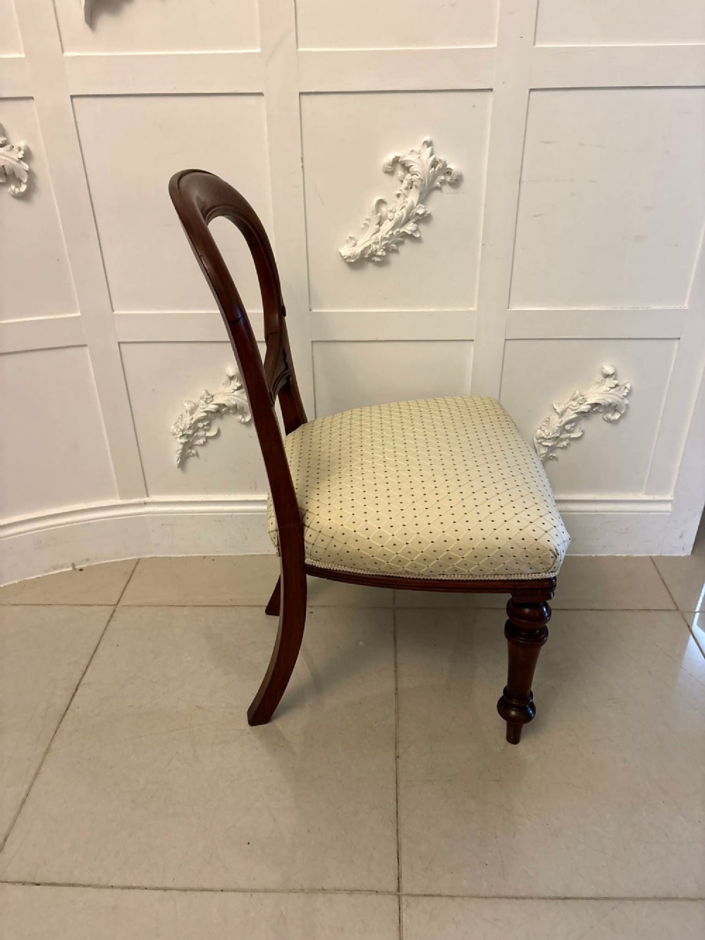 A set of four antique Victorian mahogany dining chairs featuring open balloon-shaped backrests, turned front legs, and cream patterned upholstery. View III
