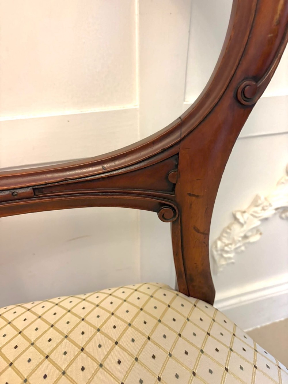 A set of four antique Victorian mahogany dining chairs featuring open balloon-shaped backrests, turned front legs, and cream patterned upholstery. View VI