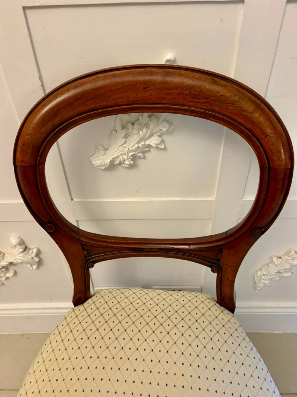 A set of four antique Victorian mahogany dining chairs featuring open balloon-shaped backrests, turned front legs, and cream patterned upholstery. View VII