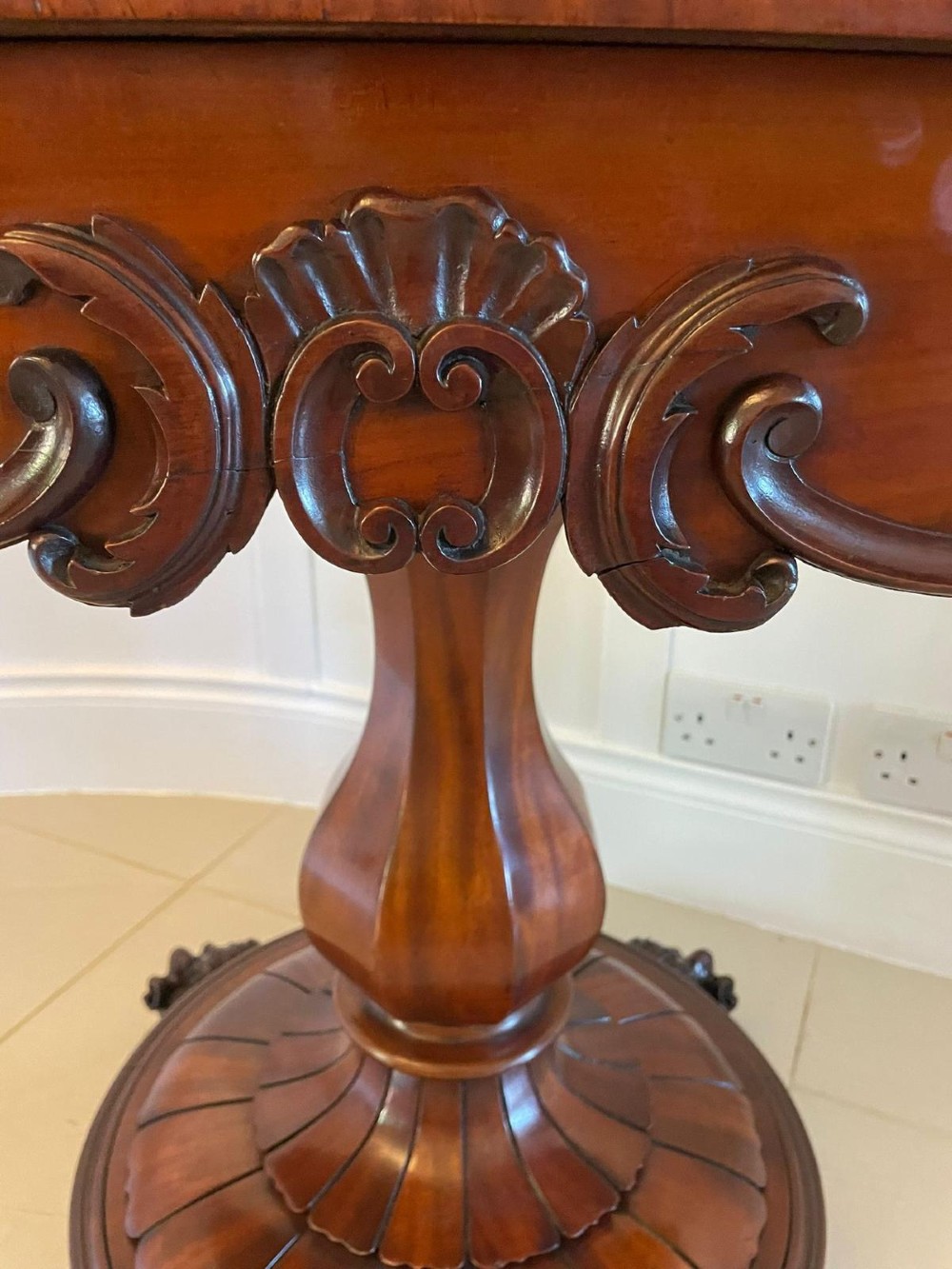 A Victorian mahogany fold-over card table featuring a rectangular top, carved apron, turned central pedestal, and four scroll feet. View III