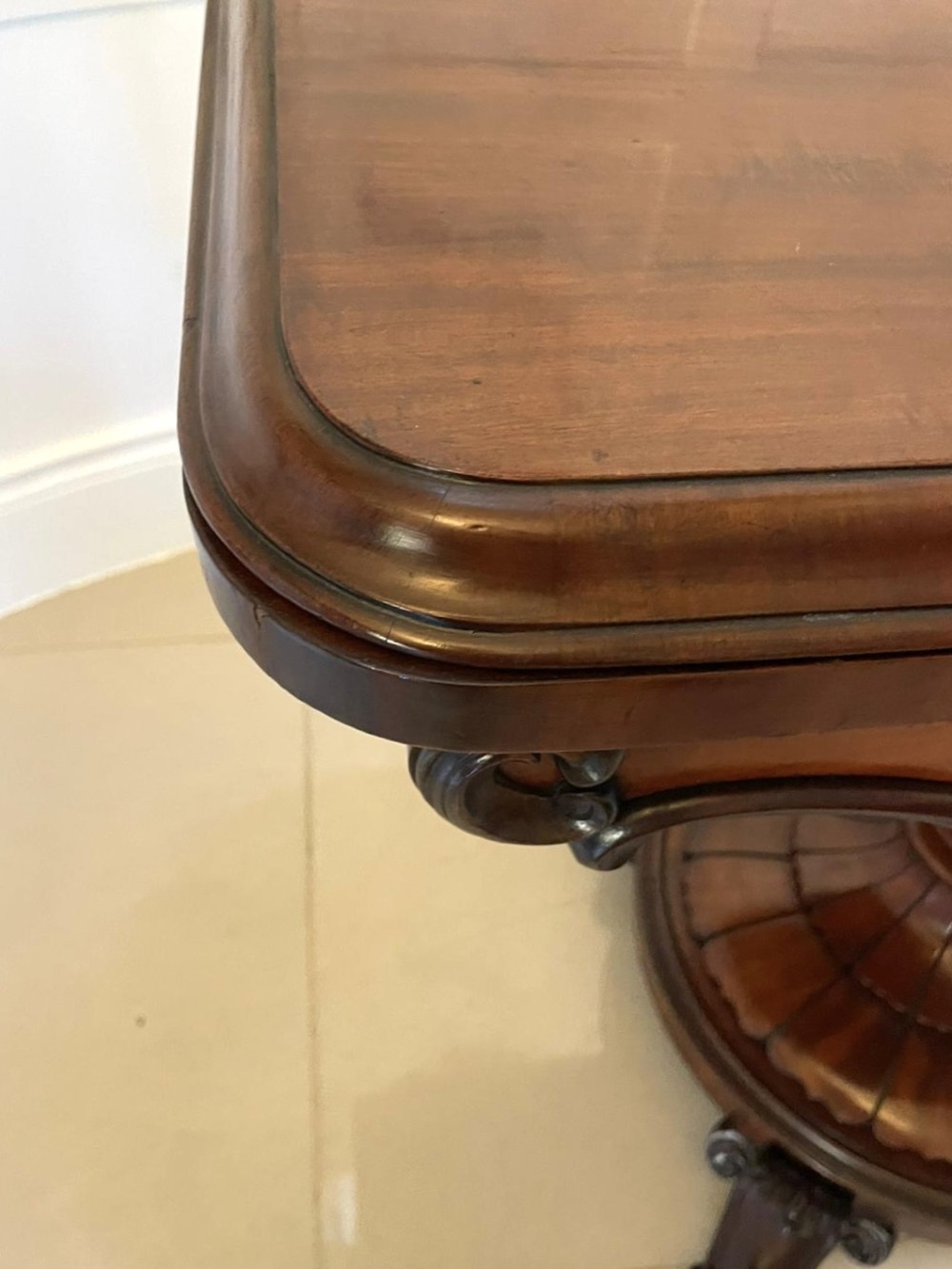A Victorian mahogany fold-over card table featuring a rectangular top, carved apron, turned central pedestal, and four scroll feet. View VI
