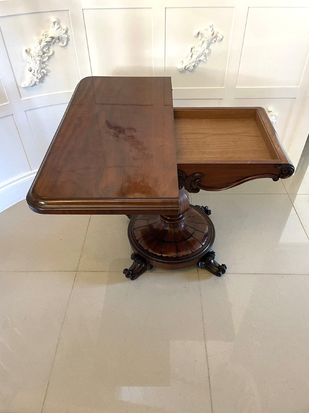 A Victorian mahogany fold-over card table featuring a rectangular top, carved apron, turned central pedestal, and four scroll feet. View IX