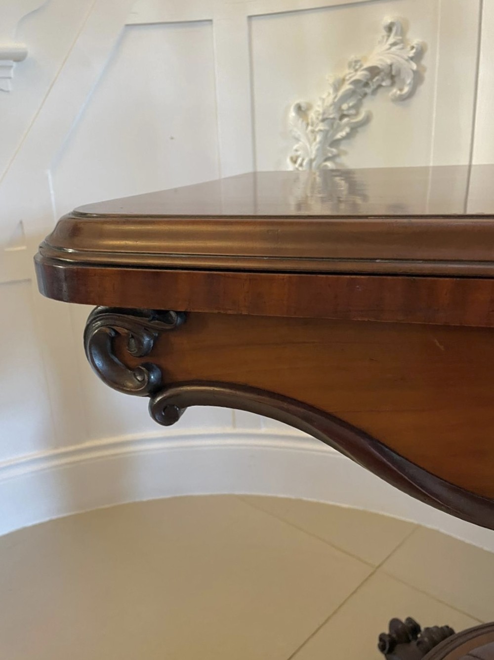 A Victorian mahogany fold-over card table featuring a rectangular top, carved apron, turned central pedestal, and four scroll feet. View XIV