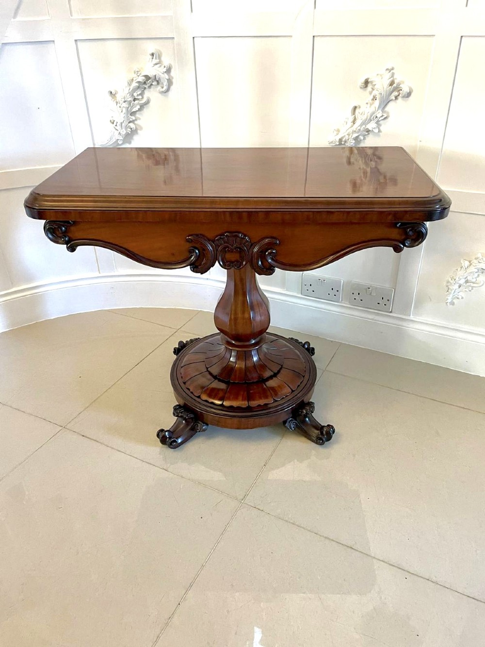 A Victorian mahogany fold-over card table featuring a rectangular top, carved apron, turned central pedestal, and four scroll feet. View XV