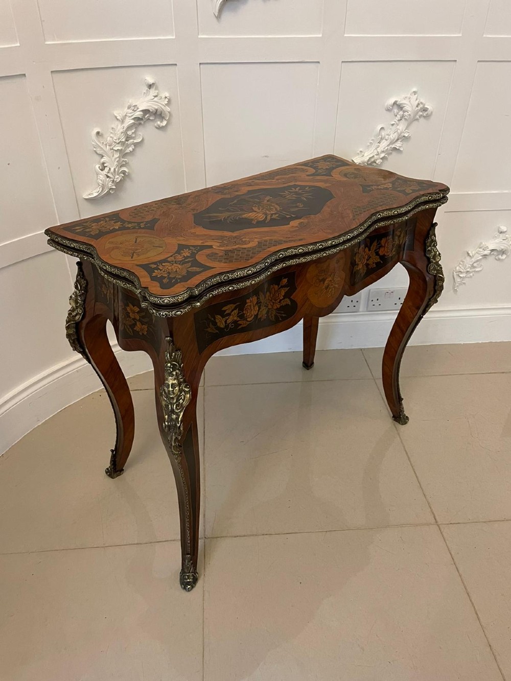 A French Rococo style kingwood card table featuring floral marquetry inlays, gilt-bronze ormolu mounts, and curved cabriole legs.