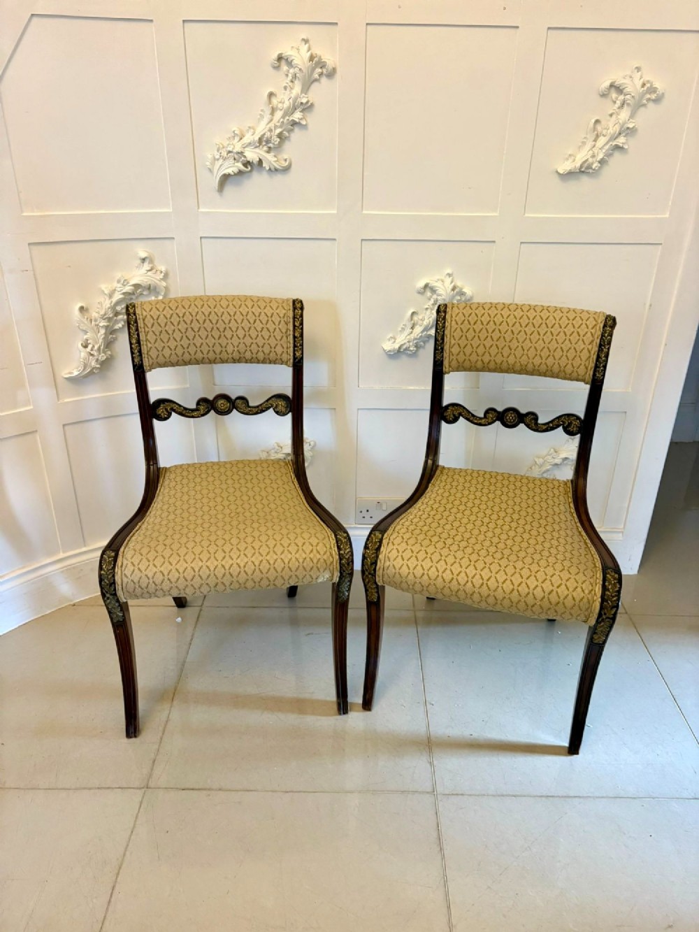 A set of eight antique Regency mahogany dining chairs featuring patterned gold upholstery, carved scrolling mid-rails, and brass detailing. View II