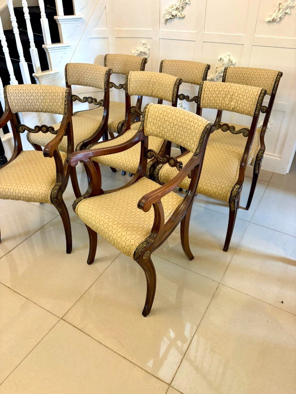 A set of eight antique Regency mahogany dining chairs featuring patterned gold upholstery, carved scrolling mid-rails, and brass detailing. View III
