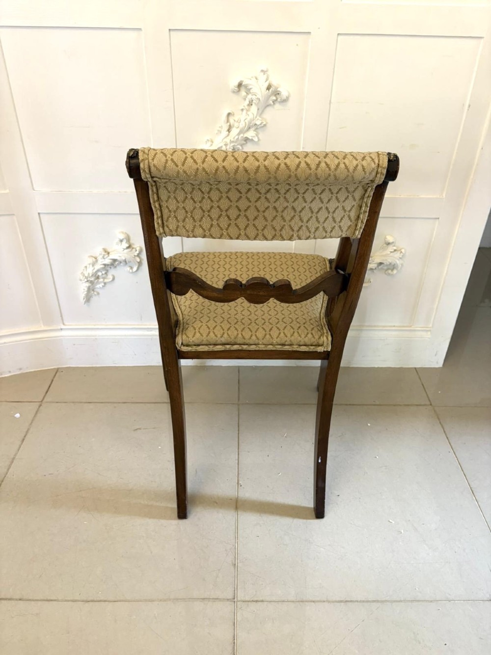 A set of eight antique Regency mahogany dining chairs featuring patterned gold upholstery, carved scrolling mid-rails, and brass detailing. View IV