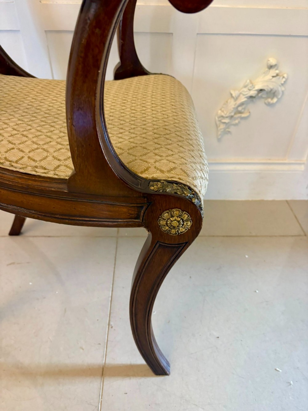 A set of eight antique Regency mahogany dining chairs featuring patterned gold upholstery, carved scrolling mid-rails, and brass detailing. View V