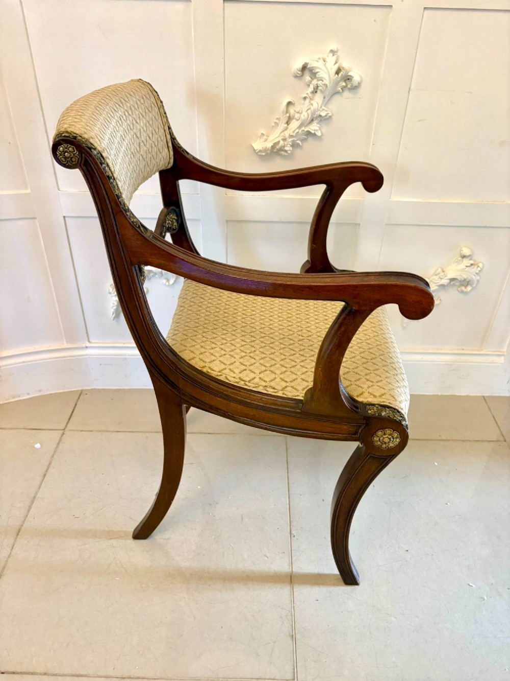 A set of eight antique Regency mahogany dining chairs featuring patterned gold upholstery, carved scrolling mid-rails, and brass detailing. View VI