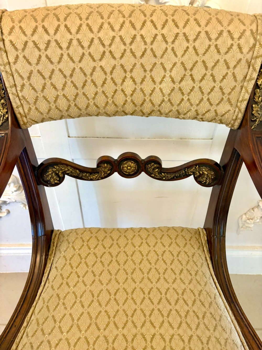 A set of eight antique Regency mahogany dining chairs featuring patterned gold upholstery, carved scrolling mid-rails, and brass detailing. View VIII