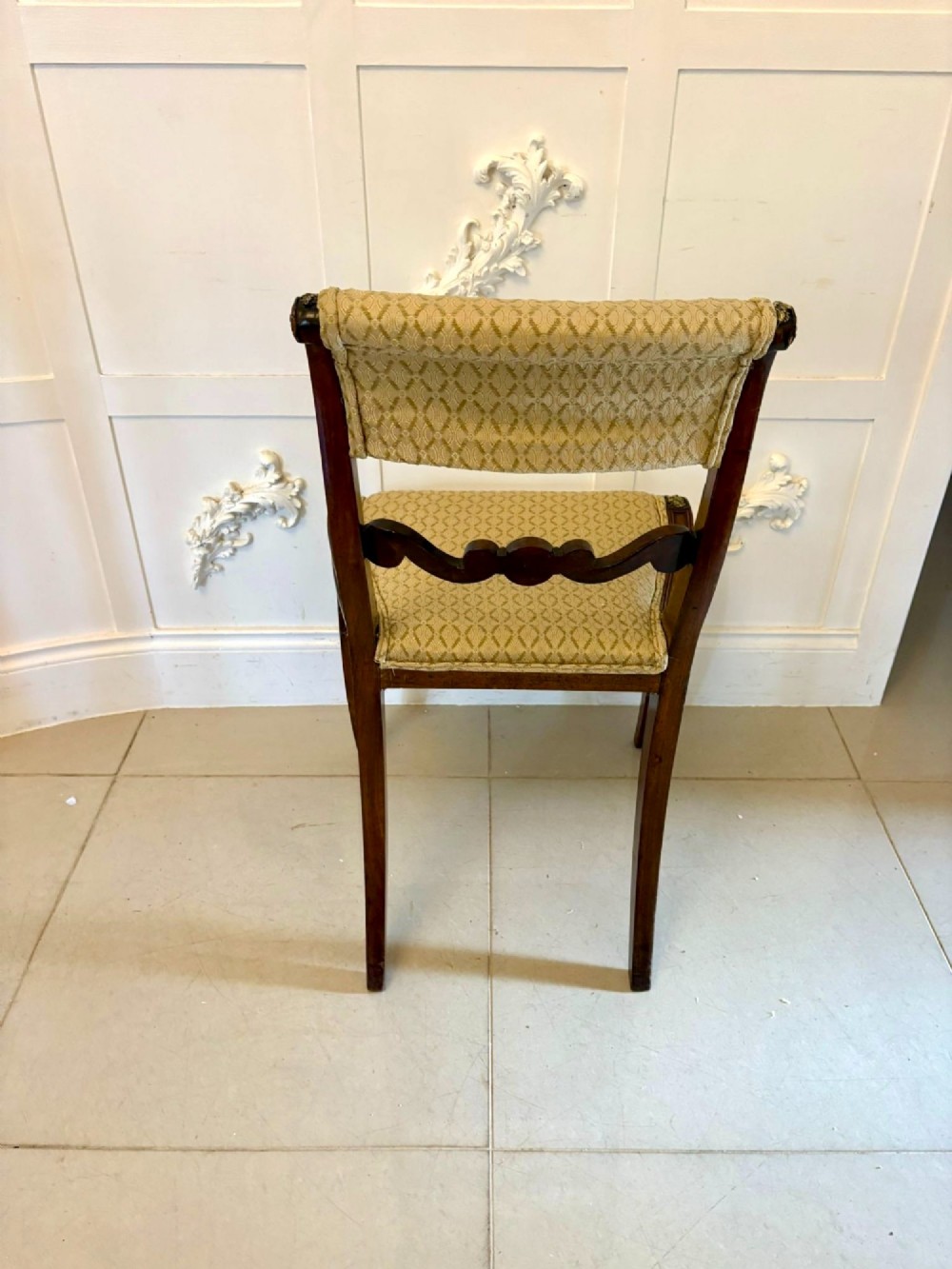 A set of eight antique Regency mahogany dining chairs featuring patterned gold upholstery, carved scrolling mid-rails, and brass detailing. View X