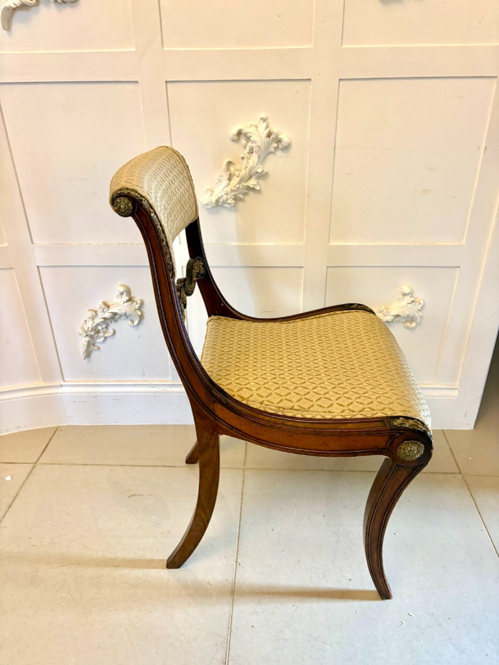 A set of eight antique Regency mahogany dining chairs featuring patterned gold upholstery, carved scrolling mid-rails, and brass detailing. View XII