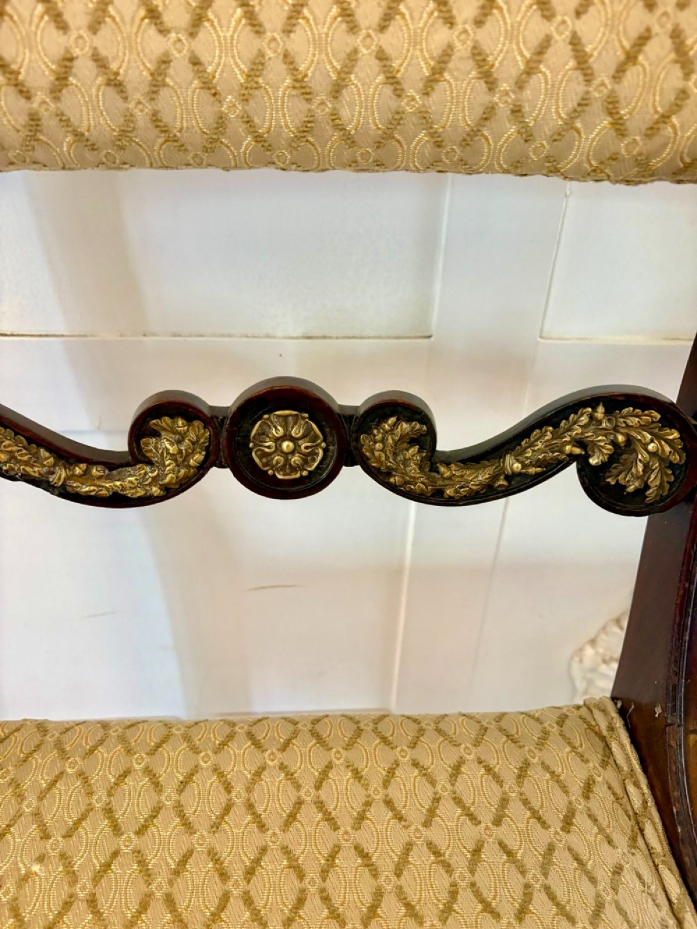 A set of eight antique Regency mahogany dining chairs featuring patterned gold upholstery, carved scrolling mid-rails, and brass detailing. View XIV