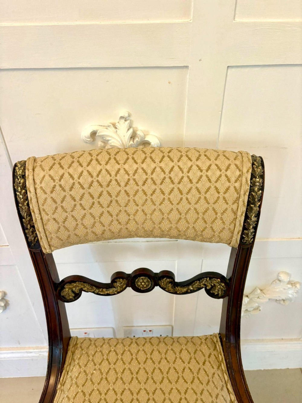 A set of eight antique Regency mahogany dining chairs featuring patterned gold upholstery, carved scrolling mid-rails, and brass detailing. View XV