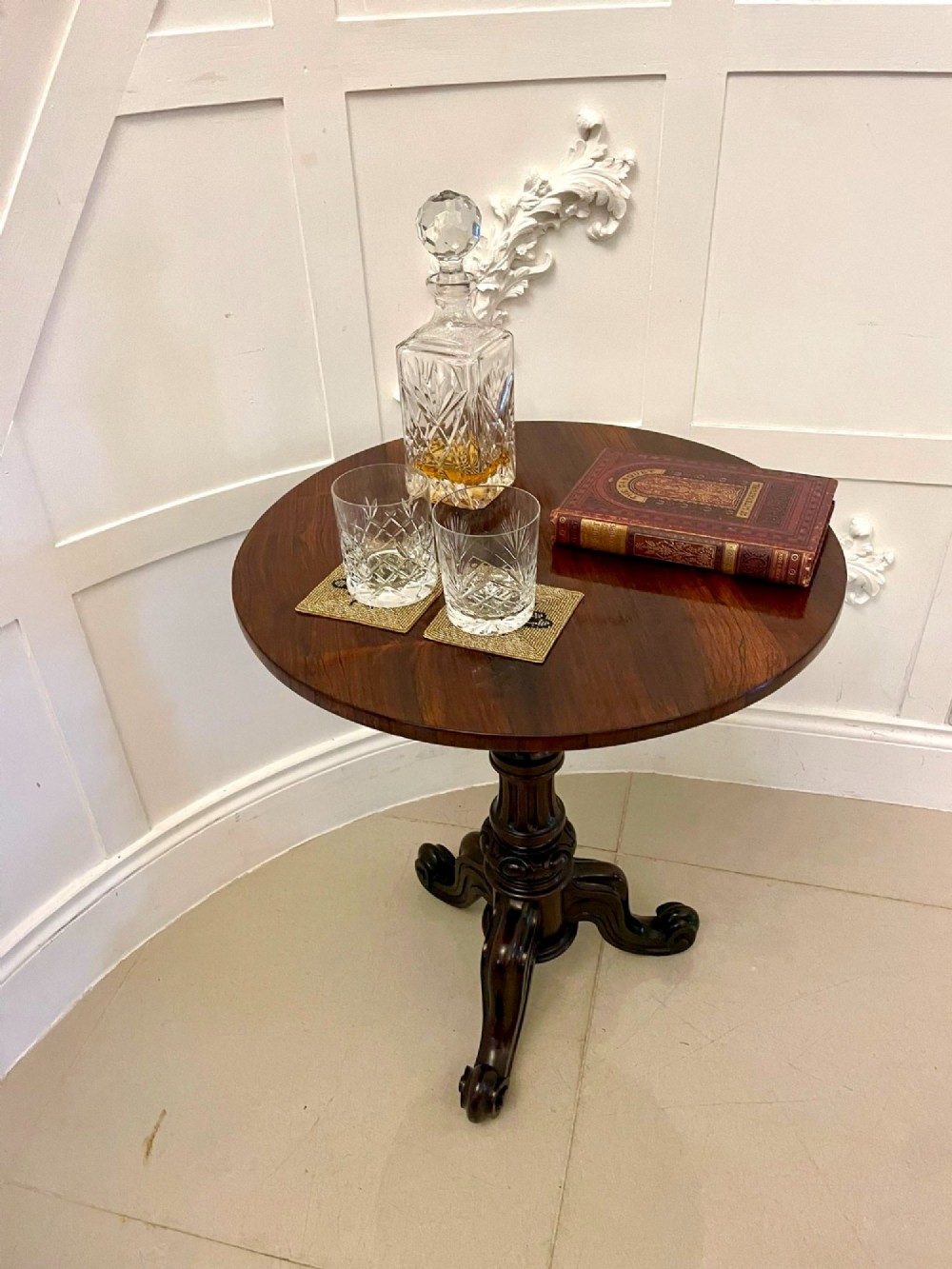 A Victorian rosewood circular lamp table shown in a tilted position, featuring a turned central column and carved tripod legs with scroll feet. View III