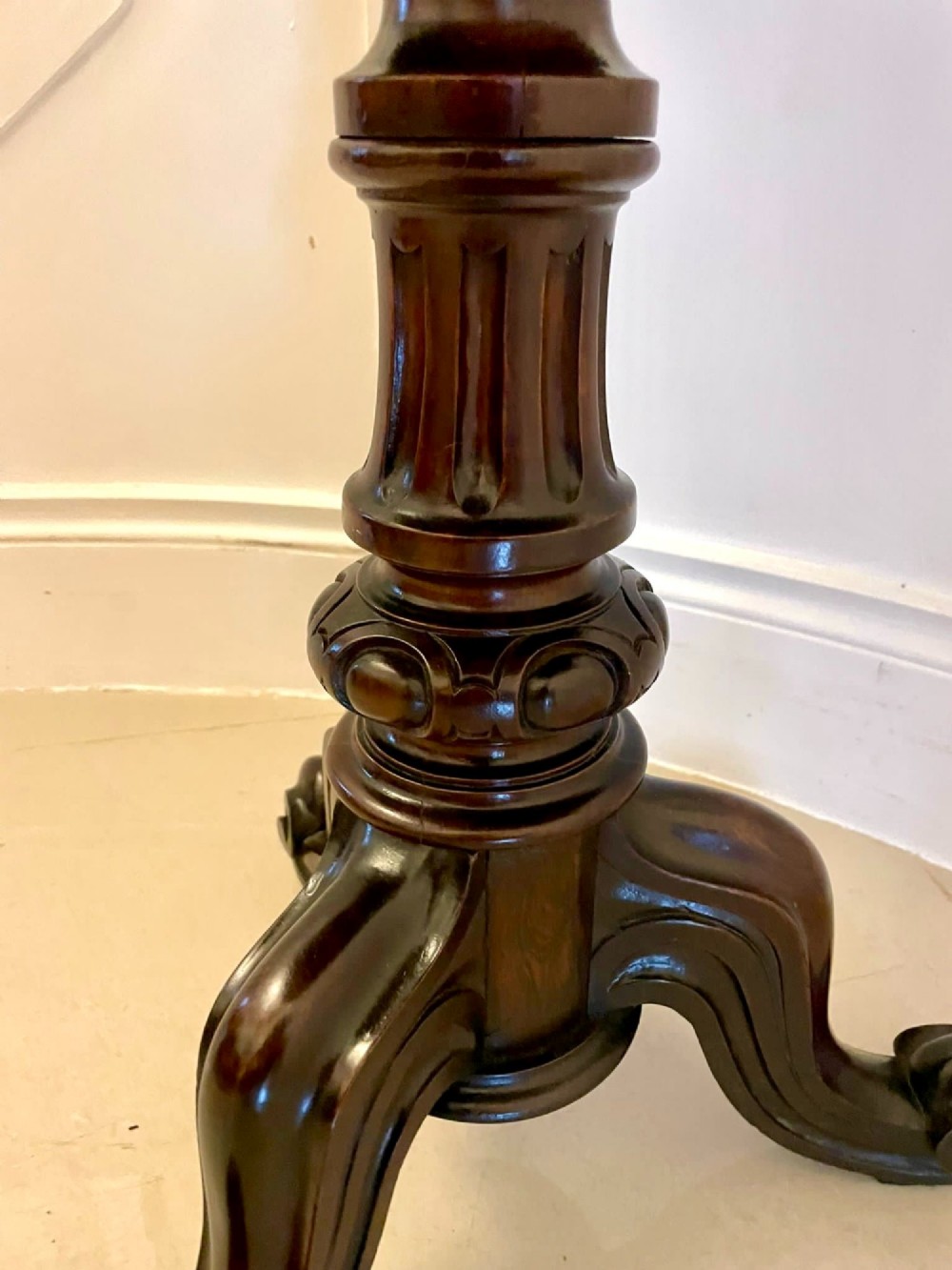 A Victorian rosewood circular lamp table shown in a tilted position, featuring a turned central column and carved tripod legs with scroll feet. View VI
