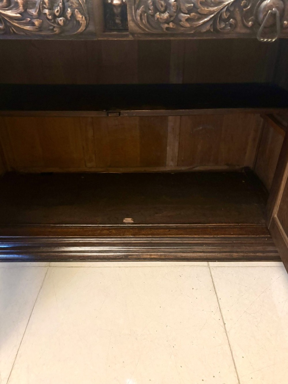 A dark carved oak sideboard featuring geometric panelled cupboard doors with central lion mask carvings and a detailed relief frieze. View VI