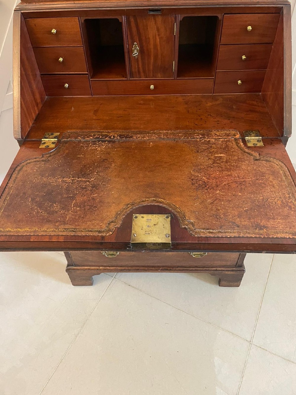An antique George II mahogany bureau bookcase featuring a mirrored door upper cabinet, a slant-front writing slope, four graduated drawers, and bracket feet. View III