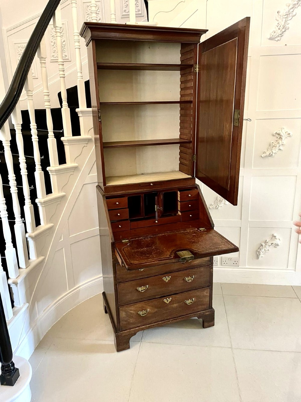 An antique George II mahogany bureau bookcase featuring a mirrored door upper cabinet, a slant-front writing slope, four graduated drawers, and bracket feet. View VII
