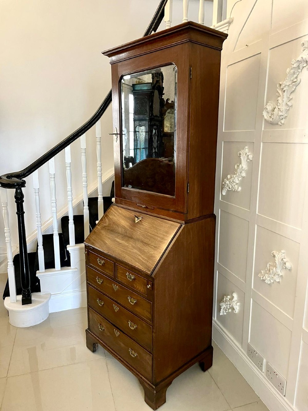 An antique George II mahogany bureau bookcase featuring a mirrored door upper cabinet, a slant-front writing slope, four graduated drawers, and bracket feet. View X